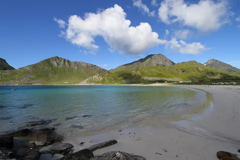 Haukland 海滩的白沙、清澈海水和绿色山坡