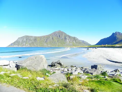 Skagsanden 白沙滩与海岸岩石，远处为 Hustinden 山峰